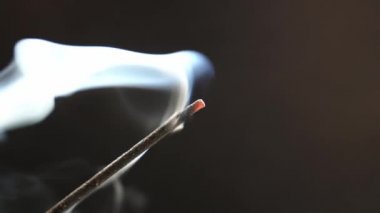 Siyah arka planda yanan aromatik bir çubuktan çıkan duman..