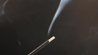 Siyah arka planda aromatik bir çubuktan çıkan duman..