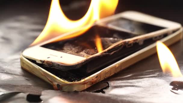 Brinnande trasig smartphone på en svart bakgrund. — Stockvideo