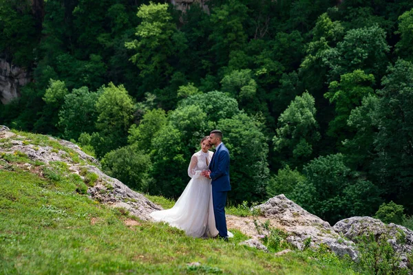 Mariage en montagne. doux jeunes mariés sur fond de forêt de montagne. — Photo