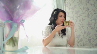 Gelinin sabahı. Beyaz pijamalı, çay içen mutlu bir kadın..