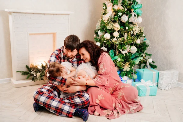 Ο μπαμπάς, η μαμά και η μικρή κόρη παίζουν στο χριστουγεννιάτικο δέντρο. — Φωτογραφία Αρχείου