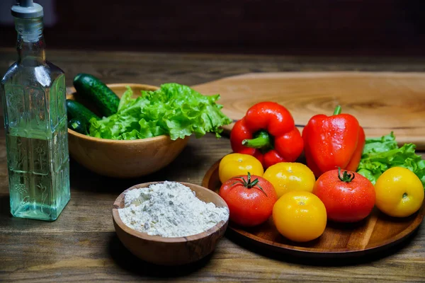Tazón de madera de harina, aceite vegetal y verduras en la mesa de la cocina — Foto de Stock