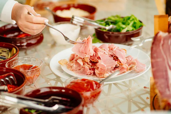 A person puts pieces of dried meat in a plate — Stock Photo, Image