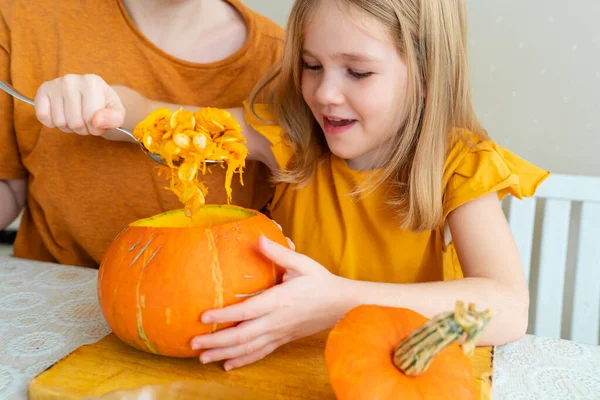 Malá holčička vytáhne lžíci semínek z dýně na Halloween. — Stock fotografie