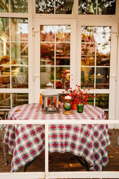 Table with checkered tablecloth and autumn decor of pumpkin, berries and candles — Stock Photo, Image