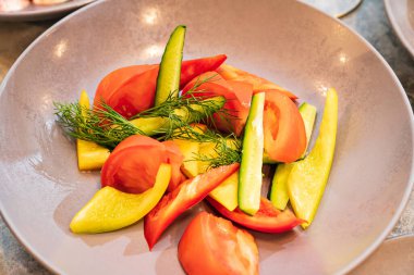 Gri bir tabakta domates, salatalık ve dolma biber.. 