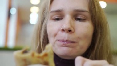 Bir kadın kafede doldurulmuş gözleme yiyor. Geleneksel Rus fast food. 