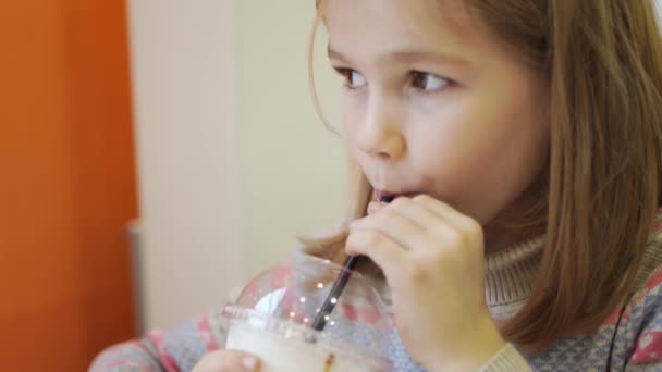Dziecko dziewczyna je wypchany naleśnik i pije koktajl w kawiarni. — Wideo stockowe