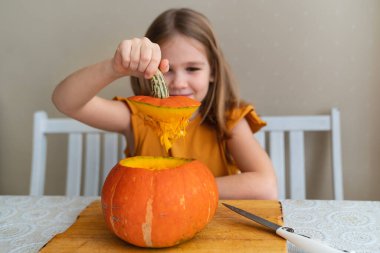 Küçük bir kız Cadılar Bayramı için balkabağından şapkasını kesiyor.. 