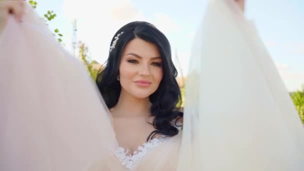 特写。美丽的黑发新娘，身穿白衣，在公园里挥舞着一条裙子. — 图库视频影像