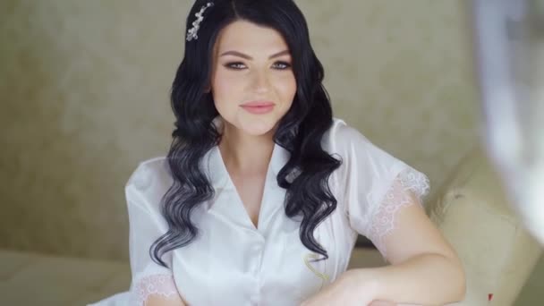 Pagi pengantin wanita. Wanita muda yang cantik dengan piyama putih di sofa dengan balon — Stok Video