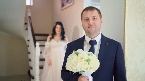 The bride approaches the groom from behind and closes his eyes. — Stock Video