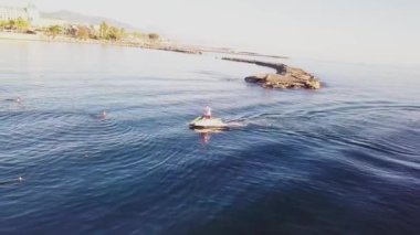 Bir adam deniz kıyısında jet ski sürüyor..