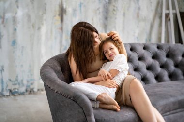 Anne kanepede kızına sarılıyor. Mutlu aile. 