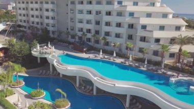 Renkli balkonları ve uzun yüzme havuzu olan çok katlı bir otel binası.. 