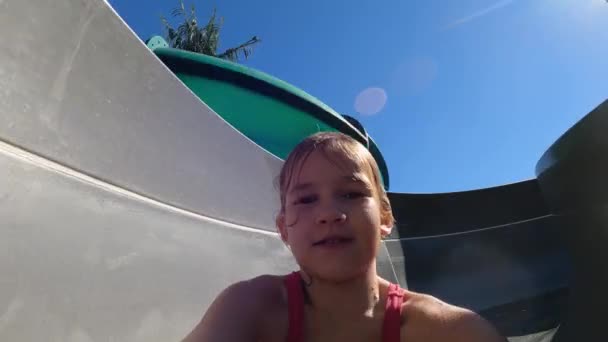 Elinde kamera olan bir kız su parkındaki kaydırağında yuvarlanıyor.. — Stok video