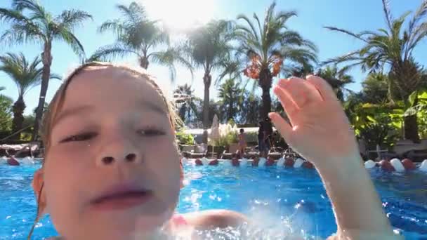 Маленька дівчинка в рожевому купальнику розважається в басейні. — стокове відео