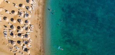 Otel plajında. Deniz kıyısında şemsiyeler ve güneşlikler.