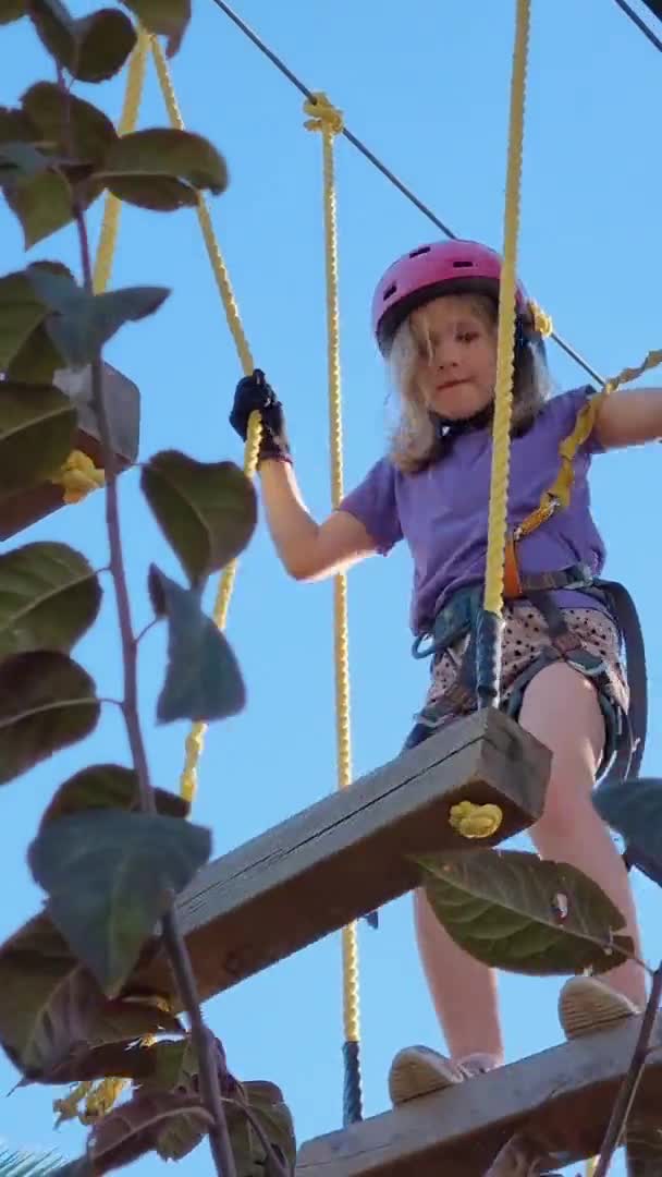 Pionowe wideo. dziewczyna się boi i przechodzi, ale deski w parku linowym. — Wideo stockowe