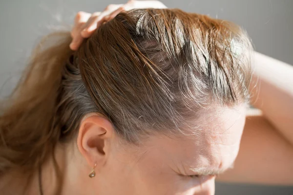 La mujer muestra las raíces crecidas del pelo gris. pintura para el pelo gris. — Foto de Stock