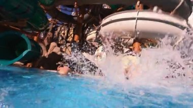 Küçük bir kız su parkındaki havuza doğru yuvarlanıyor..