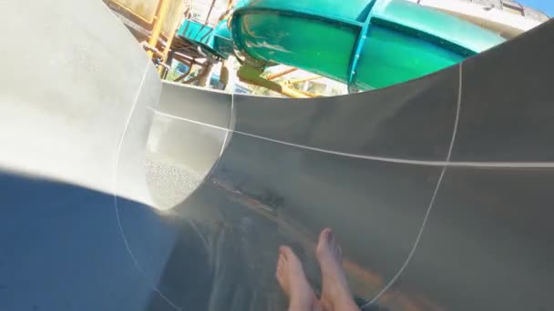 Gambe da uomo. un uomo in una macchina fotografica tra le mani rotola giù uno scivolo in un parco acquatico. — Video Stock