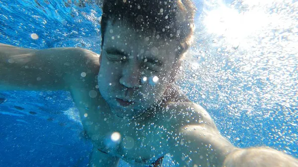 Un homme plonge dans la piscine avec une caméra à la main. tournage sous l'eau. — Photo