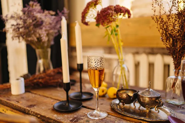 Una copa de champán, velas y cubiertos sobre una mesa de madera. — Foto de Stock