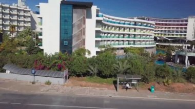 Renkli balkonları ve uzun yüzme havuzu olan çok katlı bir otel binası.. 