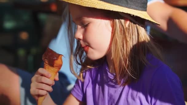 戴着草帽的一个肮脏的小女孩吃着一个装有冰淇淋的圆锥. — 图库视频影像
