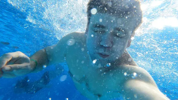 Un bărbat se scufundă în piscină cu o cameră în mâini. Filmare sub apă. — Fotografie, imagine de stoc