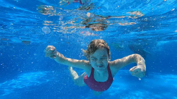 穿着粉色泳衣的小女孩在游泳池里潜水. — 图库照片