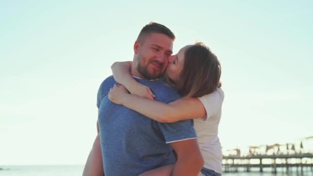 Een man en een vrouw in liefde knuffelen en plezier hebben op het zeestrand. zonnestralen — Stockvideo