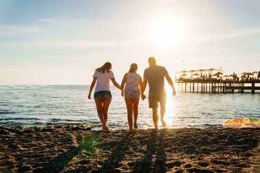 Dikiz aynası. Deniz kıyısında güneş ışığı altında bir aile. Tatil köyünde aile tatilleri.