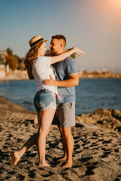 Un uomo e una donna innamorati si abbracciano sulla spiaggia. sposi novelli al resort. sole luminoso. — Foto Stock