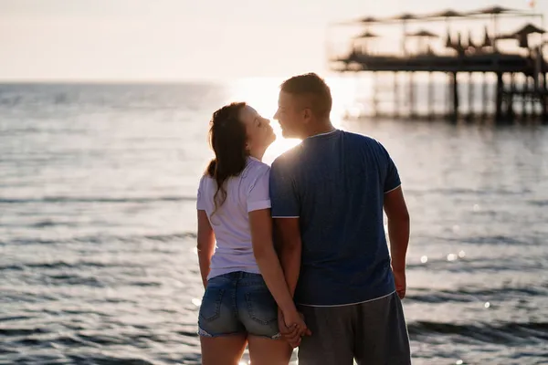 Vista trasera. siluetas de un hombre y una mujer besándose a la luz del sol en la playa. — Foto de Stock