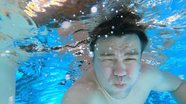 一个手里拿着相机的男人潜入了游泳池。水下射击. — 图库照片