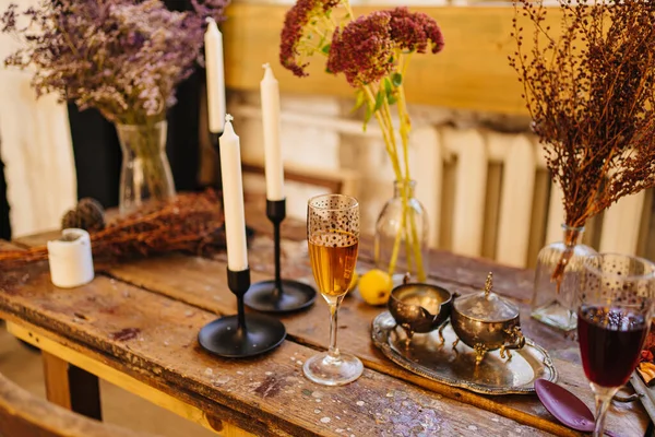 Una copa de champán, velas y cubiertos sobre una mesa de madera. — Foto de Stock