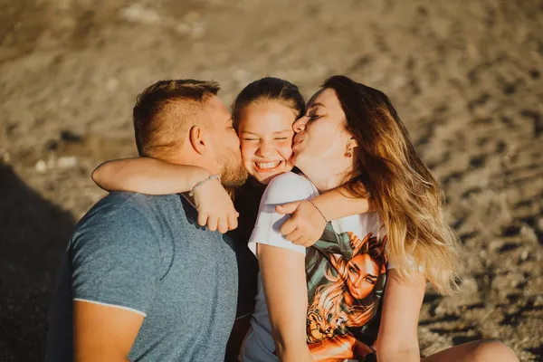 Bacio. famiglia felice sulla spiaggia. mamma, papà e figlia in vacanza nella località balneare — Foto Stock