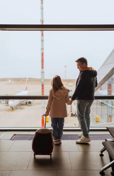 Padre e hija con una maleta junto a la ventana en el aeropuerto. — Foto de Stock