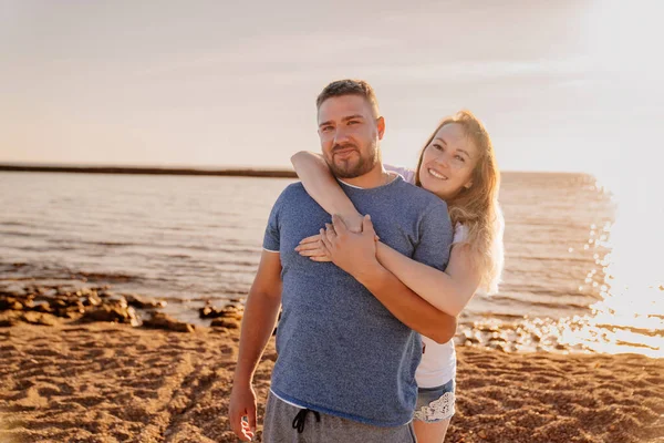 Um homem e uma mulher apaixonados abraçando e se divertindo na praia do mar. brilho solar — Fotografia de Stock