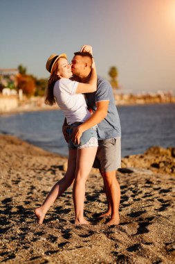 Bir adam ve bir kadın kumsalda birbirlerine sarılıyorlar. Tatil köyünde yeni evliler. parlak güneş.