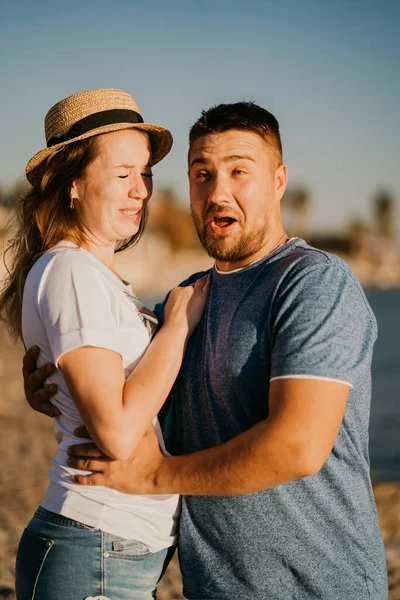 Ένας άντρας και μια ερωτευμένη γυναίκα να γελάνε αγκαλιά στην παραλία. νεόνυμφοι στο θέρετρο. — Φωτογραφία Αρχείου