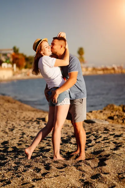 En man och en förälskad kvinna kramas på stranden. Nygifta på resorten. ljus sol. — Stockfoto