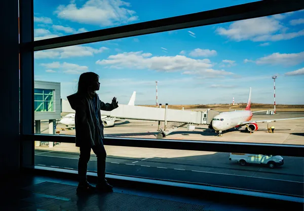 Una niña silueta de pie junto a la ventana en el aeropuerto. — Foto de Stock