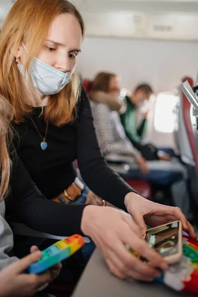 En kvinna med ett barn tittar på en film medan du flyger ett plan — Stockfoto