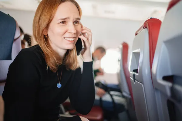 Kvinnan pratar i telefon på en plats ombord på planet. wifi för passagerare — Stockfoto