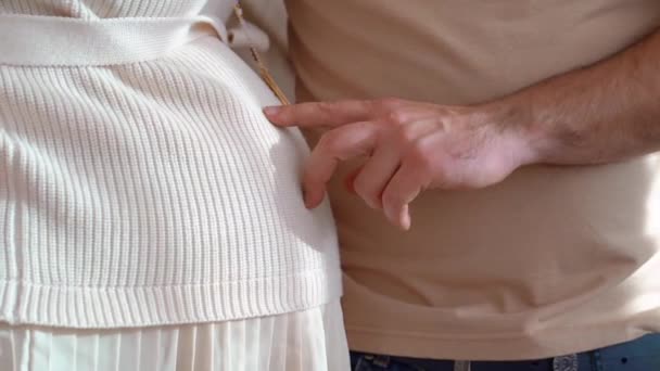 Uma mão de homem toca o abdômen de uma mulher grávida com os dedos. — Vídeo de Stock