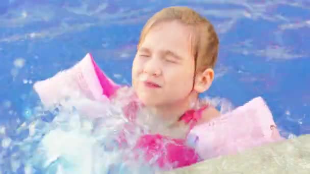 Une drôle de petite fille nage et joue dans des brassards gonflables dans une piscine — Video